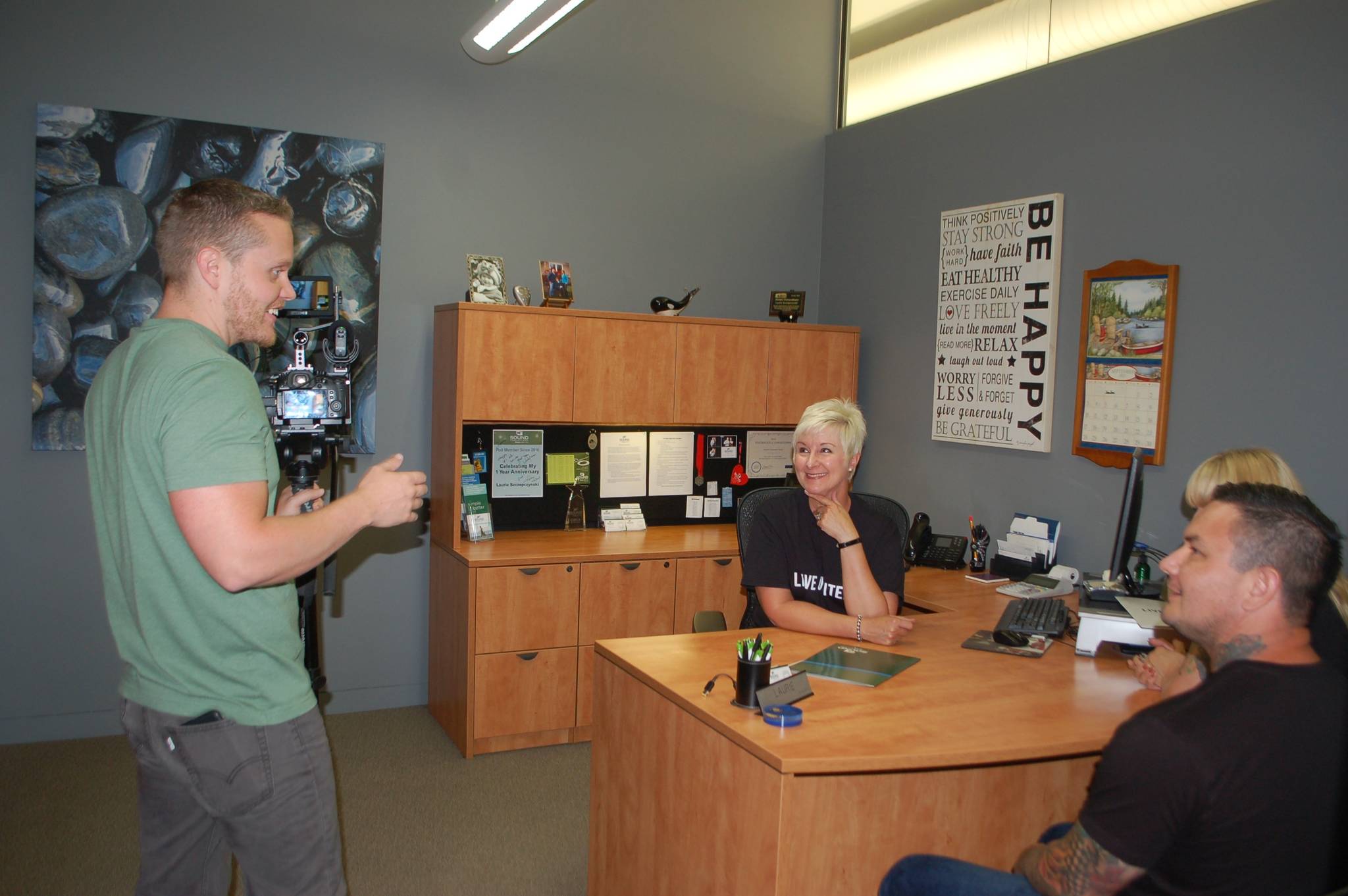 Matt Sagen, owner, producer and cinematographer of Cascadia Films, left, directs Laurie Szczepczynski of Sound Community Bank in Port Angeles and her clients Mark Ray and Haley Ray for a community video he is filming for United Way of Clallam County.