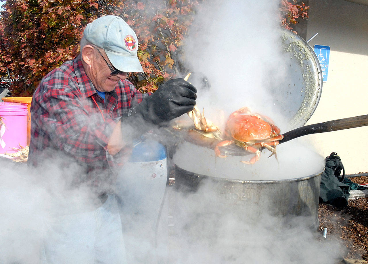 Julian McCabe helps pull cooked crab from a kettle on its way to the plate of a hungry festivalgoer in 2016. (Keith Thorpe/Peninsula Daily News)
