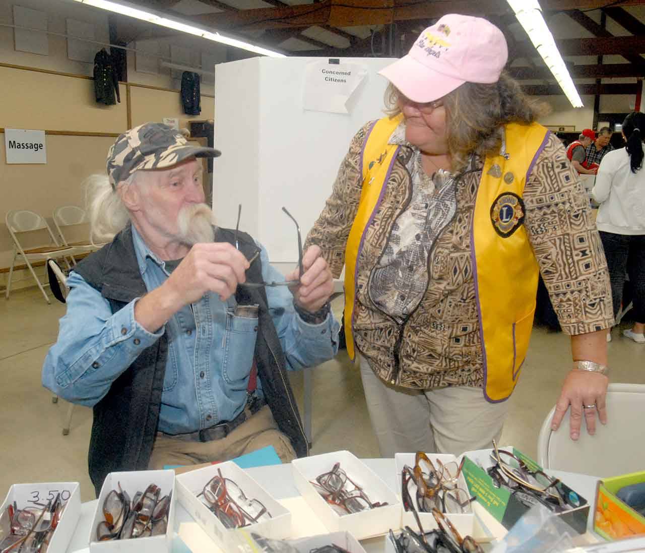 U.S. Navy veteran Ken Thela of Forks, left, shows delight in receiving a free pair of glasses from Sequim Valley Lions Club member Lee Martin during Thursday’s Voices for Veterans Stand Down at the Clallam County Fairgrounds in Port Angeles. (Keith Thorpe/Peninsula Daily News)