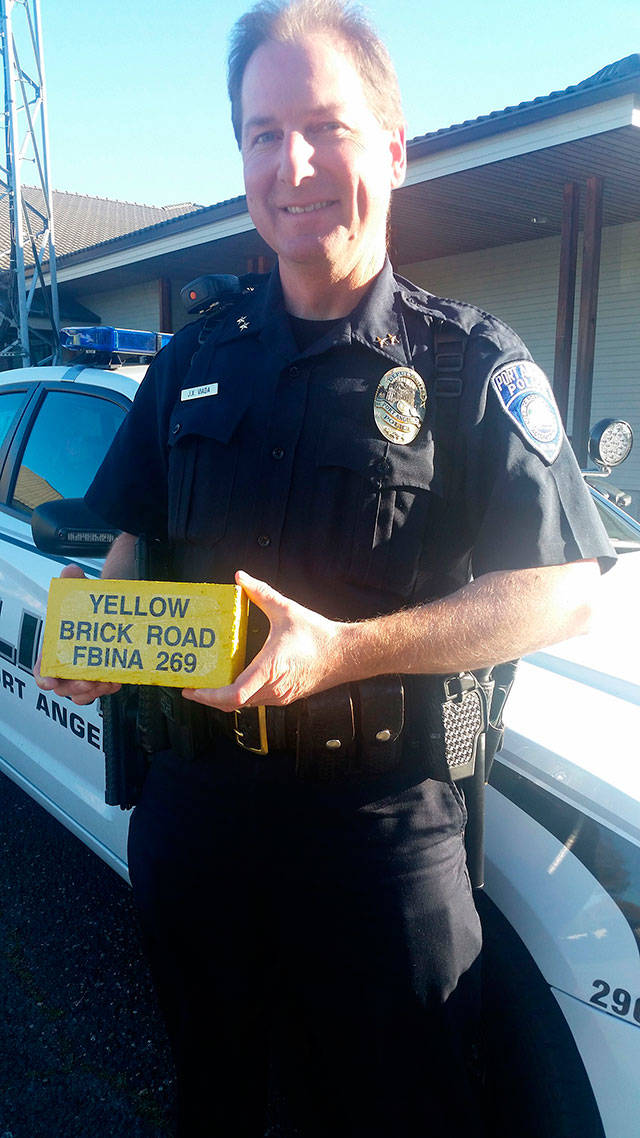 Port Angeles Deputy Police Chief Jason Viada with a yellow brick of the FBI National Academy. The brick symbolizes the completion of the academy’s “Yellow Brick Road” obstacle course, part of its physical training. (Brian Smith/Port Angeles Police Department)