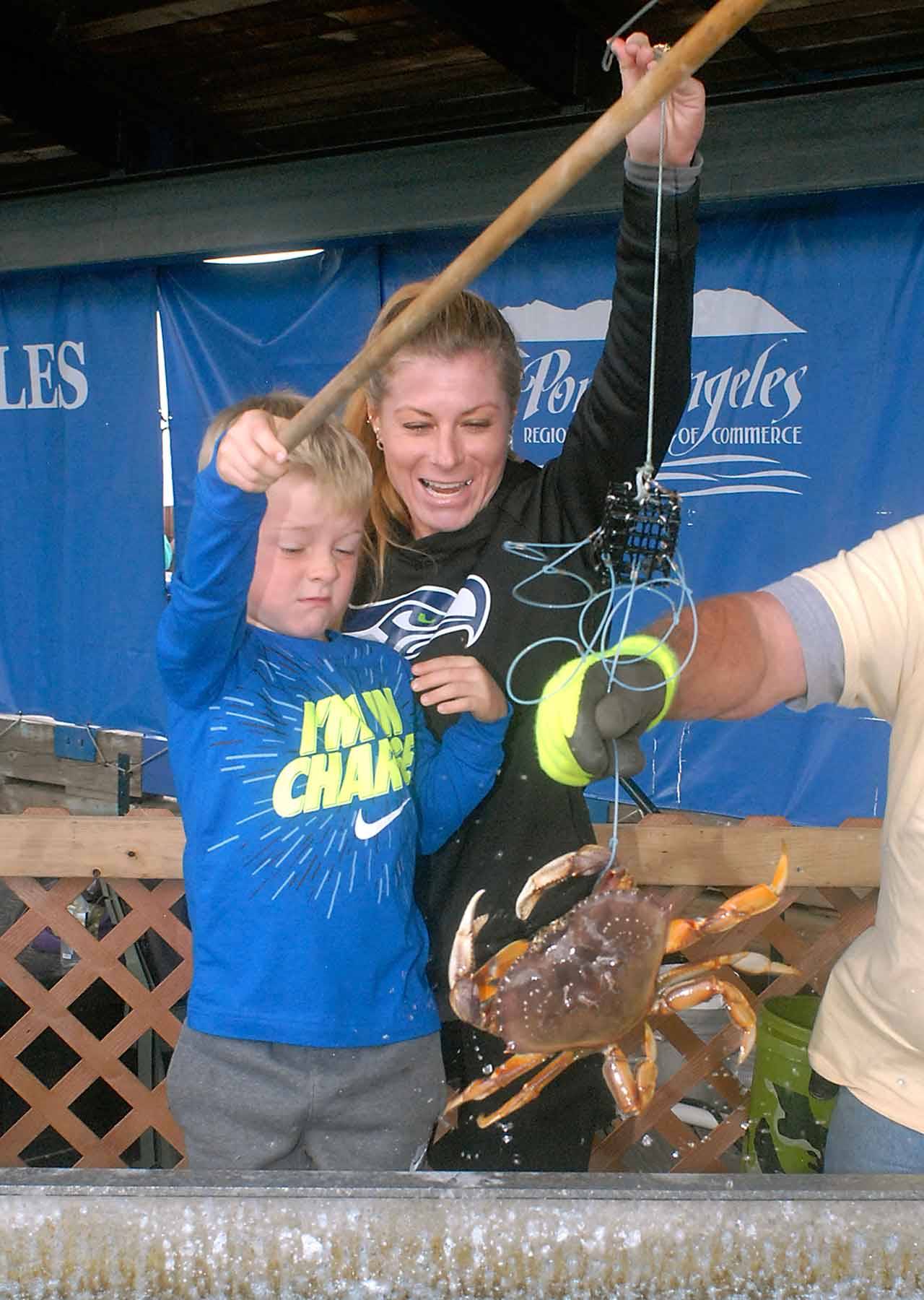Marshall Springob, 11, winces as his mother, Angie Springob of Port Angeles, shows delight as the pair collaborated to catch a crab during the Dungness Crab & Seafood Festival crab derby Friday at Port Angeles City Pier. (Keith Thorpe/Peninsula Daily News)