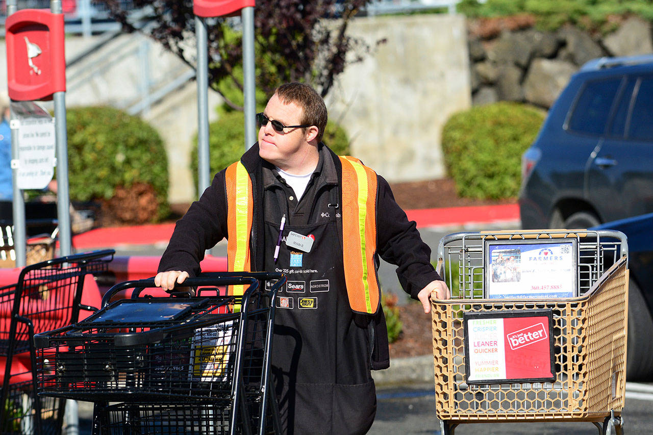 Ryan Brooke, who has Down syndrome, collects carts at the Safeway on Lincoln Street in Port Angeles on Monday. He is one of thirteen employees with a developmental disability at the grocery store. (Jesse Major/Peninsula Daily News)