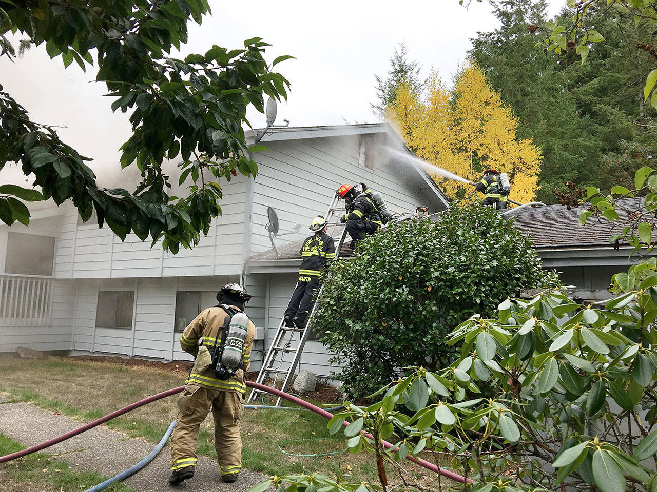 Firefighters spray water at a fire through a window of a residence in the 70 block of Chimacum Creek Road on Monday morning. The fire claimed two pets, a cat and a dog. (East Jefferson Fire & Rescue)