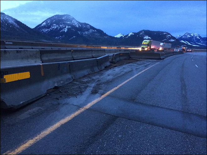 A semi truck broke through the jersey barrier after hitting a boulder that slid down on Interstate 90 at Snoqualmie Pass. (The Associated Press)