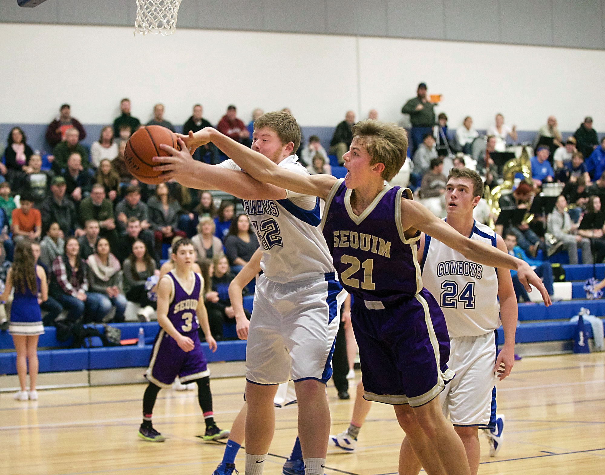 Sequim's Jackson Oliver (21) knocks the ball out of the hands of Chimacum's Lane Dotson and forces a turnover as Chimacum's Brendon Naylor (24) looks on. (Steve Mullensky/for Peninsula Daily News)