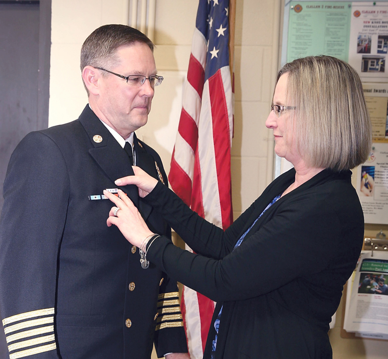 Jennifer Phillips pins a ribbon on her husband during a ceremony at the February board meeting of Clallam County Fire District No. 2. Chief Sam Phillips earned the designation of “Chief Fire Officer” from the Center of Public Safety Excellence. ()