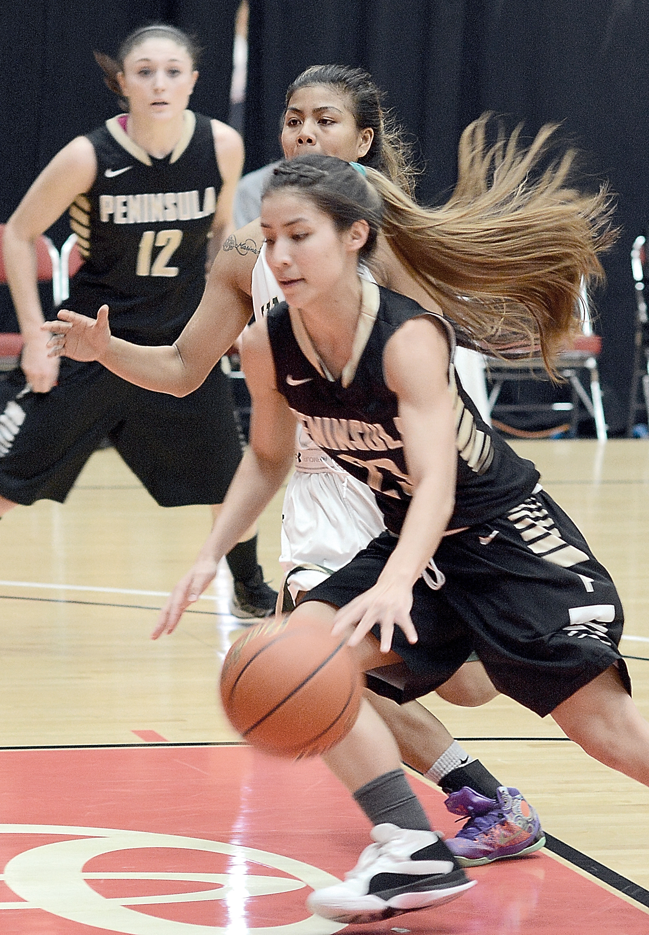 Peninsula's Miranda Schmillen (with ball) dribbles in the lane while covered by an Umpqua defender during Peninsula's 84-70 NWAC semifinal victory over the Riverhawks Monday at the Toyota Center in Kennewick. (Rick Ross/Peninsula College)