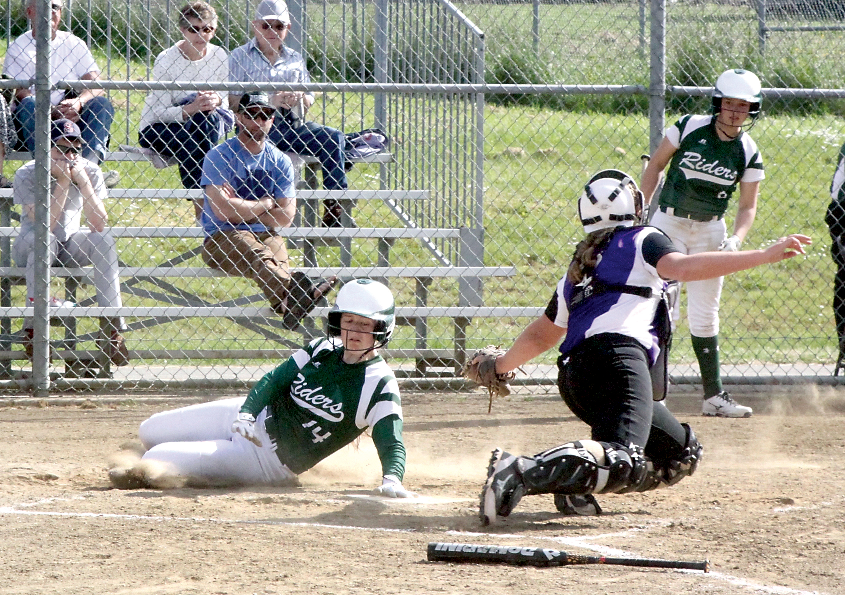 Lauren Lunt slides safely into home plate for Port Angeles' seventh run of the game as North Kitsap catcher Lamara Villard tries to apply a tag. Kylee Reid of Port Angeles watches from the background. (Dave Logan/for Peninsula Daily News)