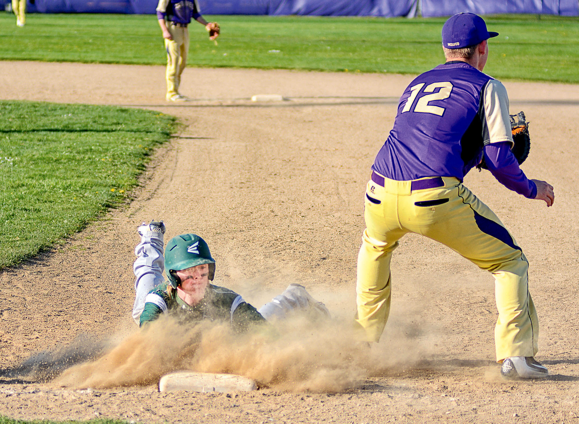 Port Angeles' Curan Bradley slides back to first base as Sequim's Daniel Harker awaits a throw. Bradley was voted to the All-Olympic League 2A first team. (Jay Cline/for Peninsula Daily News)