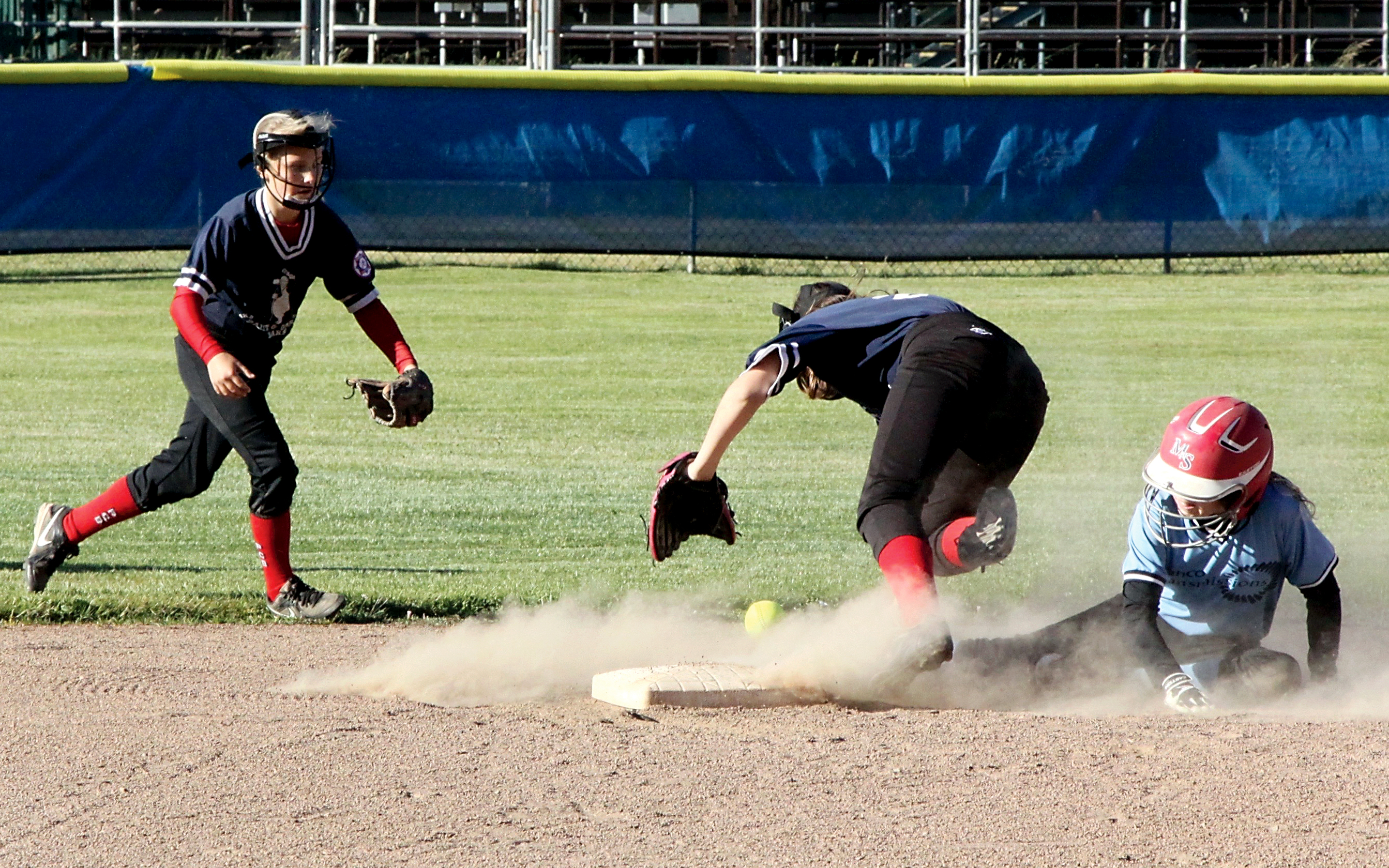 Tranco Transmission's Teagan Clark slides safely into second base as Paint and Carpet Barn's shortstop Destiny Smith races to grab and errant throw and Katelyn Glass backs up the play. (Dave Logan/for Peninsula Daily News)
