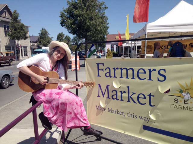 Sallie “Spirit” Harrison performs songs at the Sequim Farmers Market on Saturday during her long walk across the North Olympic Peninsula. ()