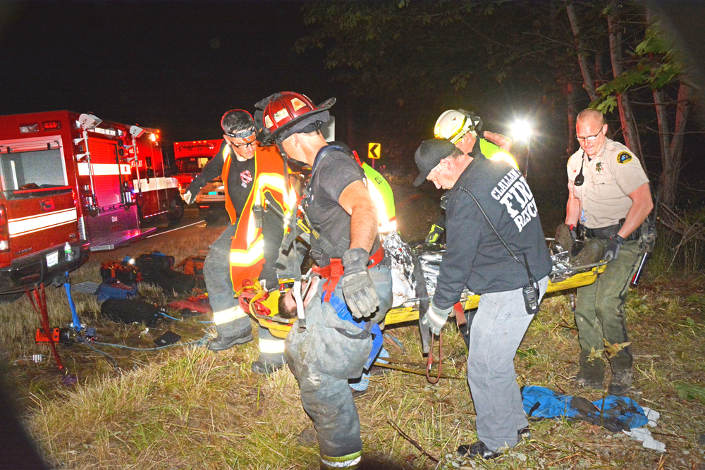 A rescue crew carries an unnamed victim up from the crash site on Black Diamond Road on Friday morning. From left