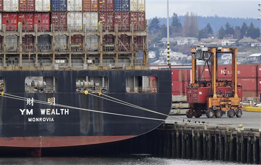 A cargo container mover carries a container next to a cargo ship operated by Yang Ming Marine Transport Corp. at the Port of Tacoma today
