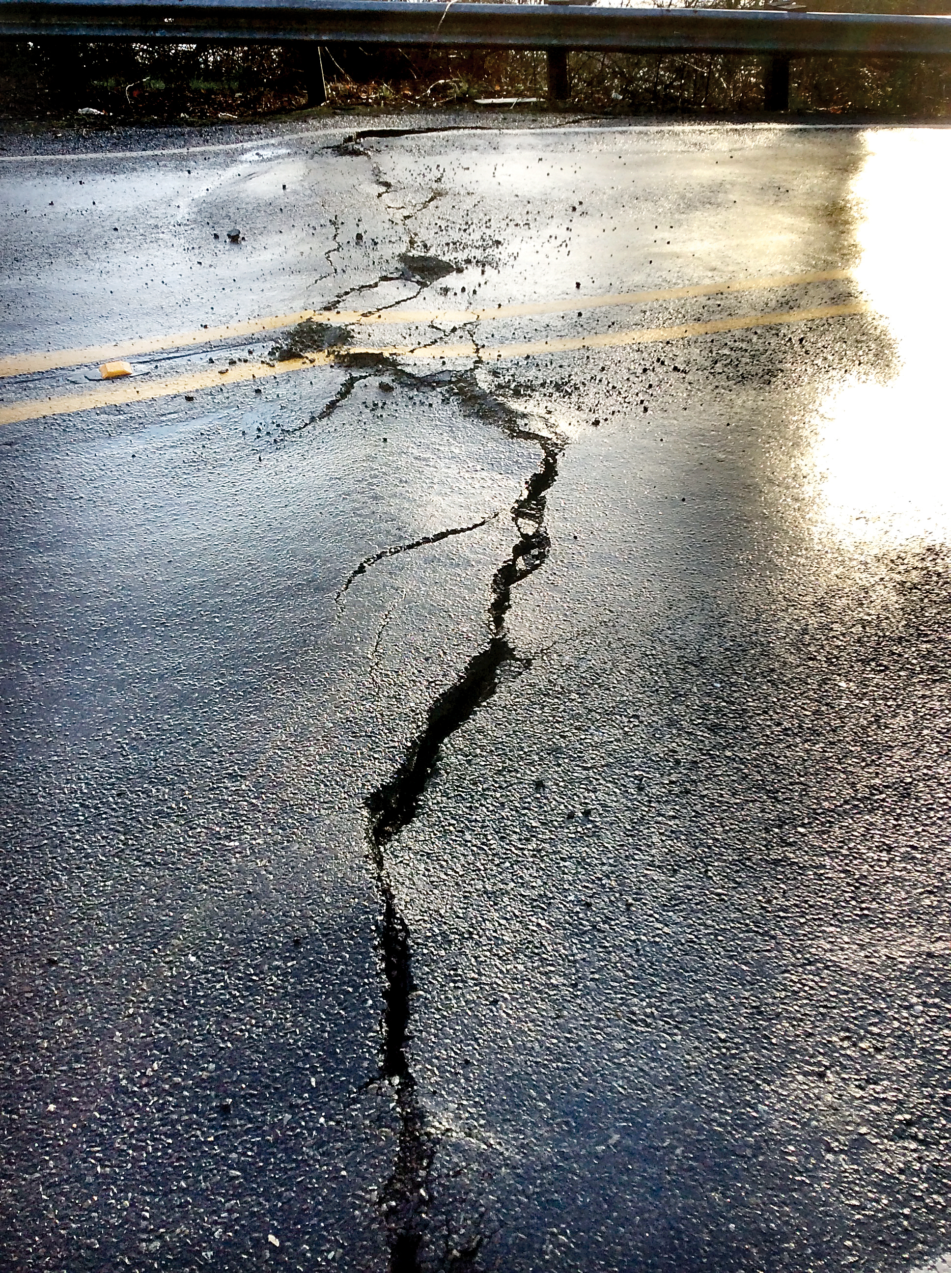 A crack forms in a section of state Highway 112 where part of the road has begun sliding at mile marker 2.3. The road remained open to traffic Tuesday. (State Department of Transportation)