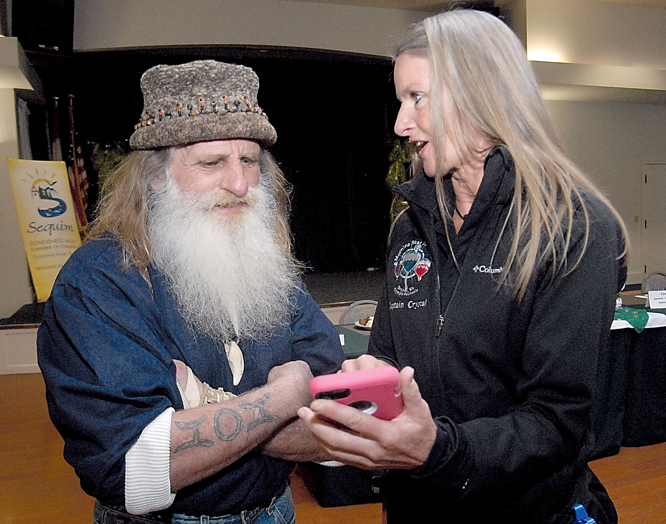 Reality television star Mick Dodge looks at photos on a cellphone Tuesday with pilot Crystal Stout of Sequim-based Morning Star Balloon Co. — Keith Thorpe/Peninsula Daily News ()