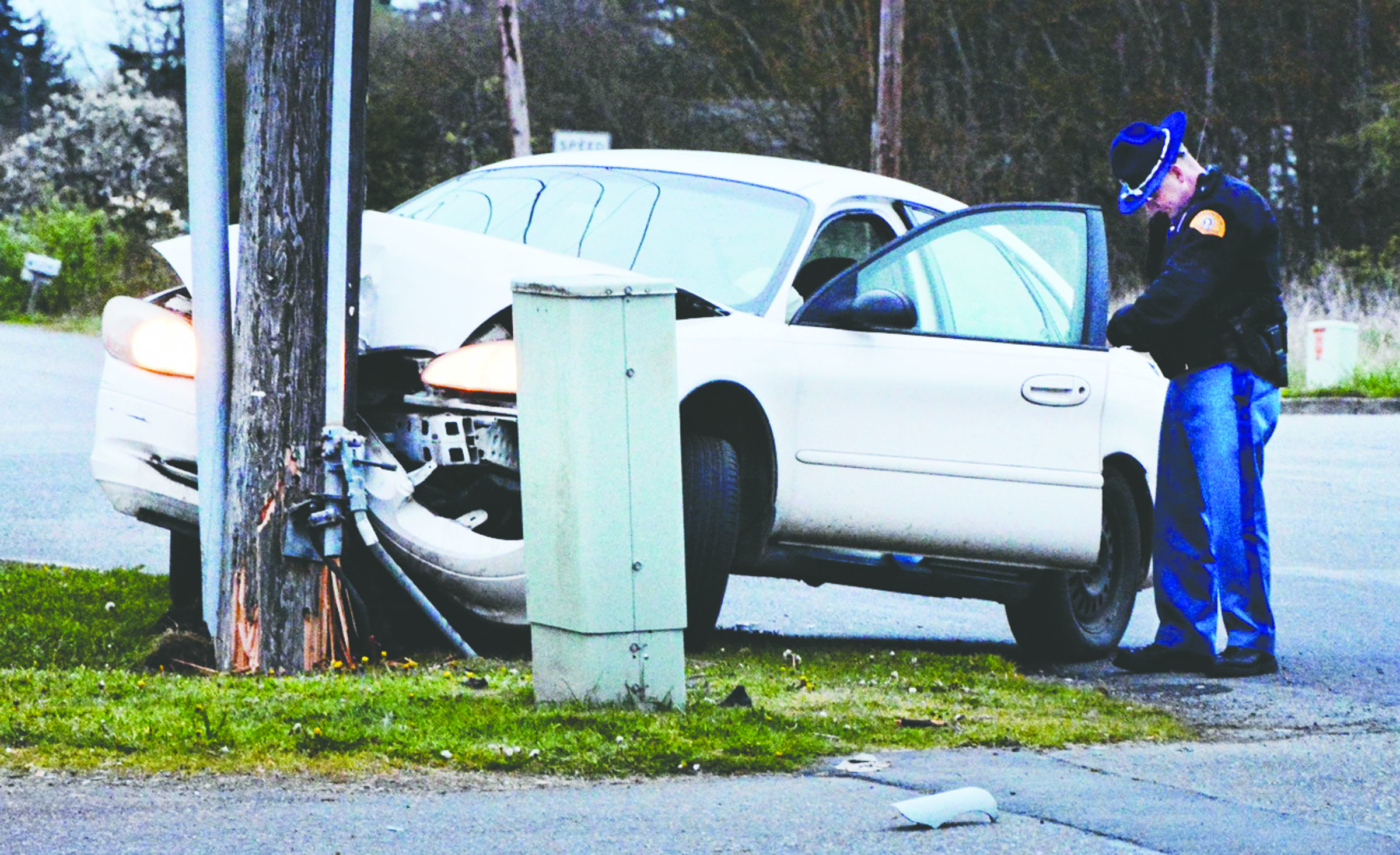 A State Trooper fills out paperwork as he examines a 2001 Ford Taurus that struck a power pole near the intersection of Mount Pleasant Road and U.S. Highway 101 on Sunday at about 7:38 p.m. The wreck cut off power to residents in the Deer Park area until noon Monday.  Jay Cline/Clallam County Fire District No. 2 ()