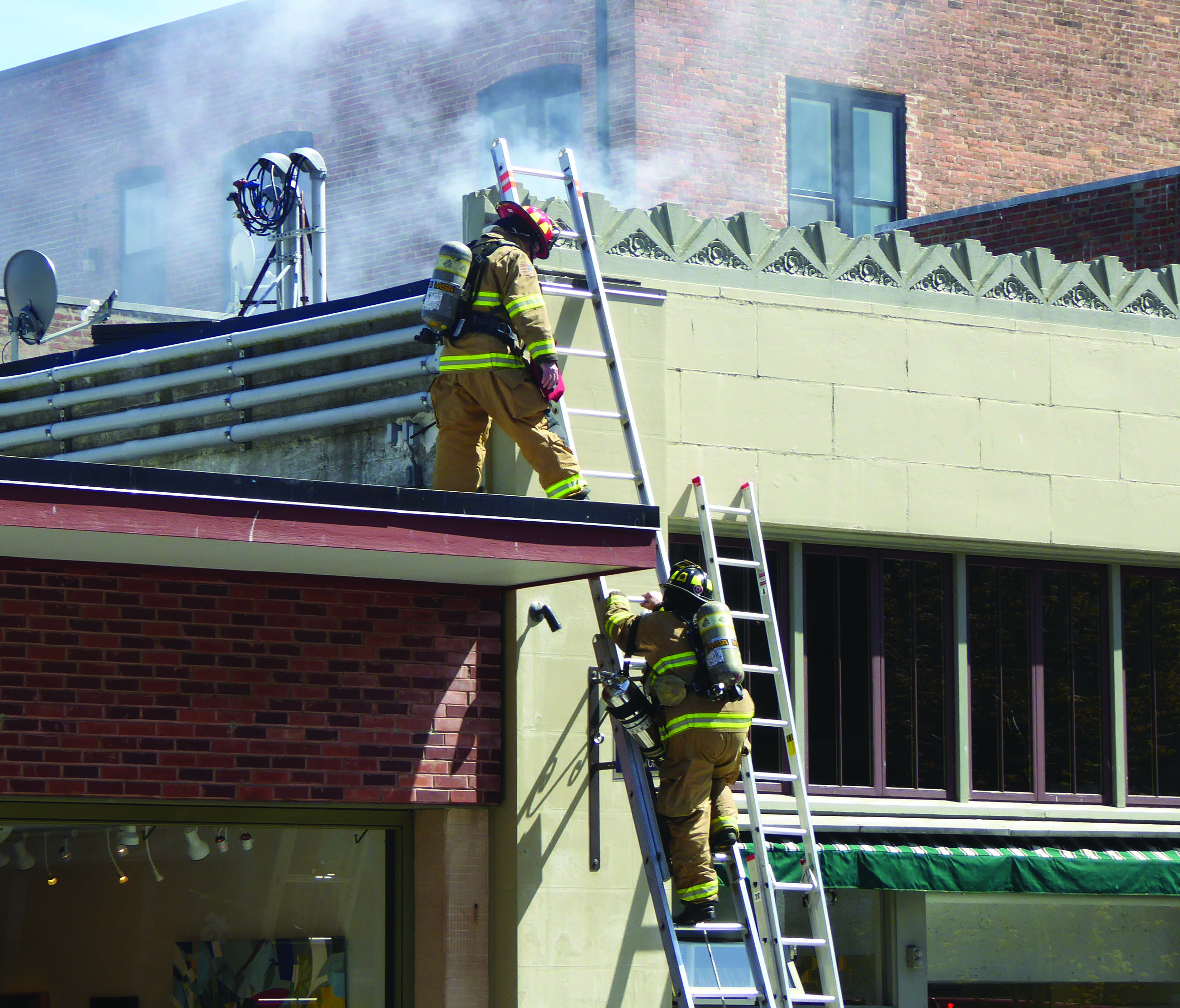 Firefighters with East Jefferson Fire-Rescue climb to the roof of 232 Taylor St. in Port Townsend on Sunday to combat a chimney fire. (Charlie Bermant/Peninsula Daily News)