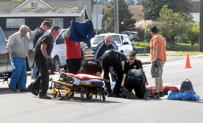 Port Angeles emergency workers assist a pedestrian who was struck by a vehicle at Lauridson Boulevard and Chase Street behind Jefferson Elementary School on Tuesday. (Keith Thorpe/Peninsula Daily News)