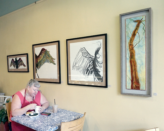 Lehani's employee Debbie Holt takes a lunch break next to student paintings part of this month's Art Wave project. Aside from Lehani's
