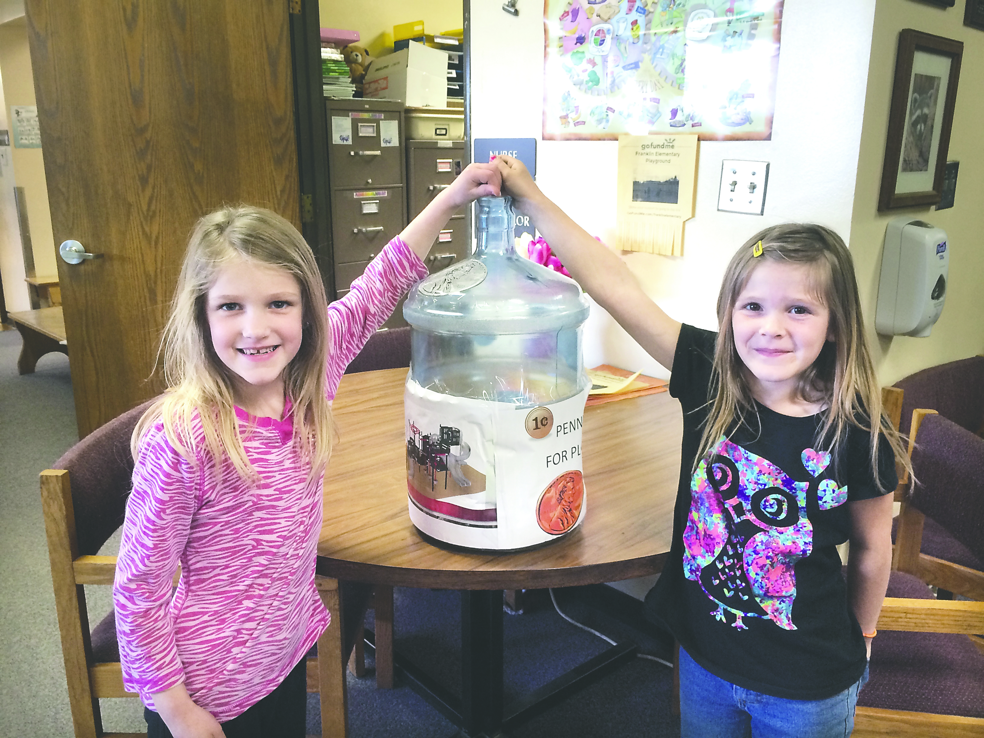 Franklin Elementary School students Audrey Muxen and Kendra Dickinson donate their change to the playground fund. (Port Angeles School District photo)