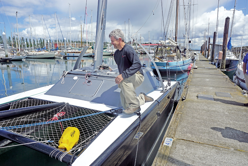 Brandon Davis of Turn Point Design inspects the 24-foot carbon catamaran that is entered in the second Race to Alaska. The boat was the first local entry for the 2015 race but turned back due to too much rudder strain in high winds. — Charlie Bermant/Peninsula Daily News ()