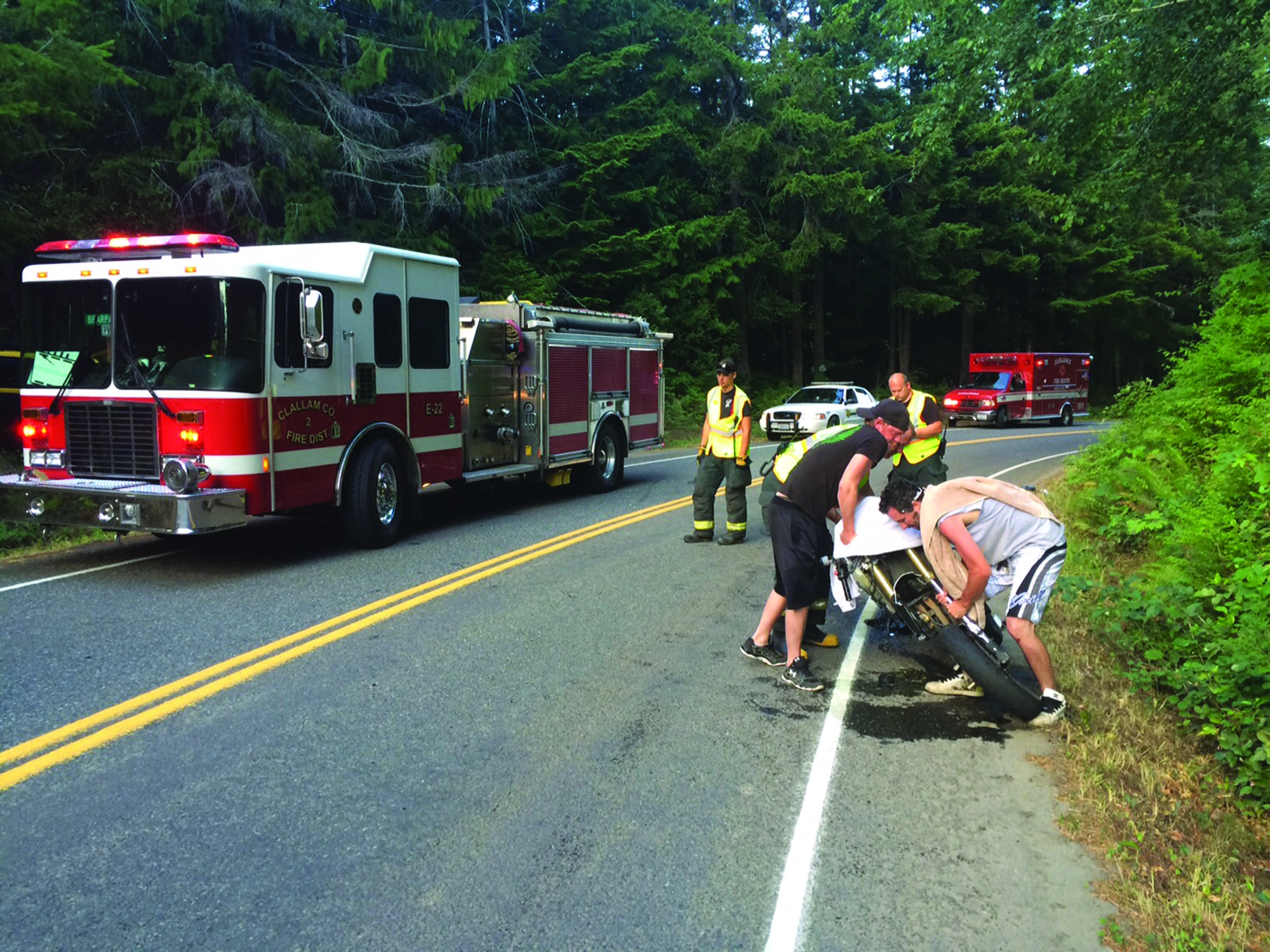 A group of men right a Suzuki motorcycle after it collided with a Dodge van on East Beach Road on Saturday at about 6:30 p.m. The motorcyclist was transported to Olympic Medical Center in Port Angeles with nonlife-threatening injuries. Clallam County Fire District No. 2 responded to the crash. No other injuries were reported. (Clallam County Fire District No. 2)