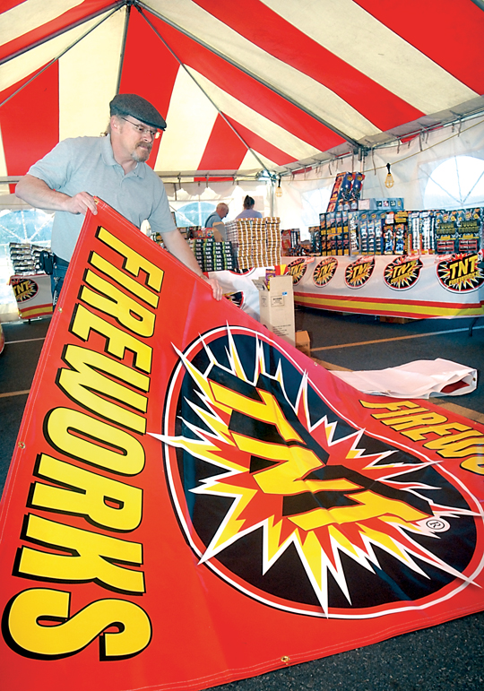 Sheldon Koehler unfurls a sign Tuesday that will advertise the fireworks tent operated by the Clallam County Amateur Radio Club in the parking lot of the Port Angeles Walmart store. (Keith Thorpe/Peninsula Daily News)