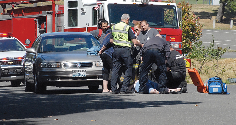 Police and paramedics assist a female pedestrian who was struck by a car at Ninth and G streets in Port Angeles on Wednesday. — Keith Thorpe/Peninsula Daily News ()