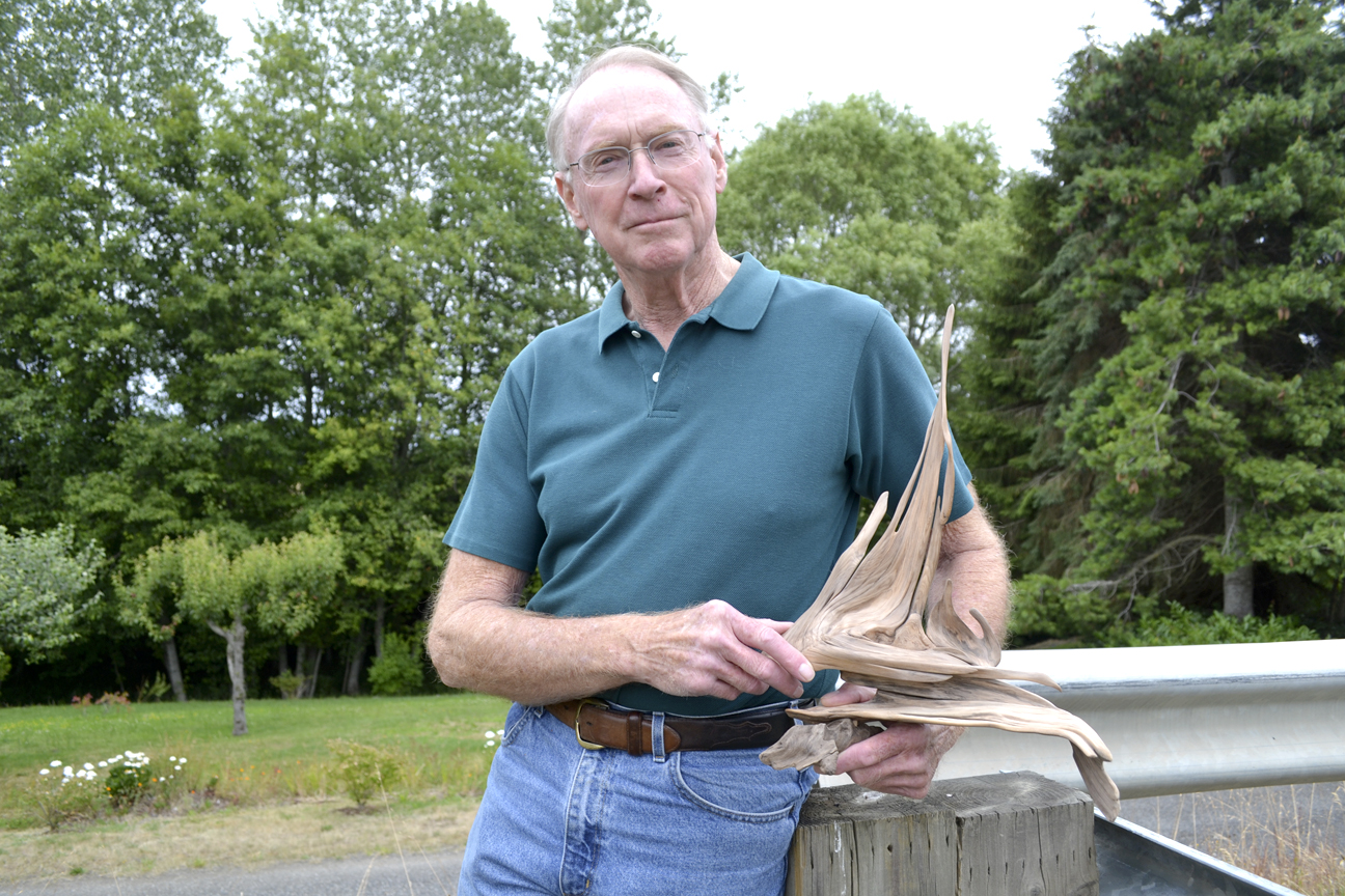 Don Berger holds an art piece created by fellow driftwood sculptor Cliff Peterson that he plans to finish for him by today and the start of the Olympic Driftwood Sculptors' annual Lavender Weekend show. Peterson asked Berger to finish it for him due to health issues so that he could give it to his health provider. (Matthew Nash/Olympic Peninsula News Group)