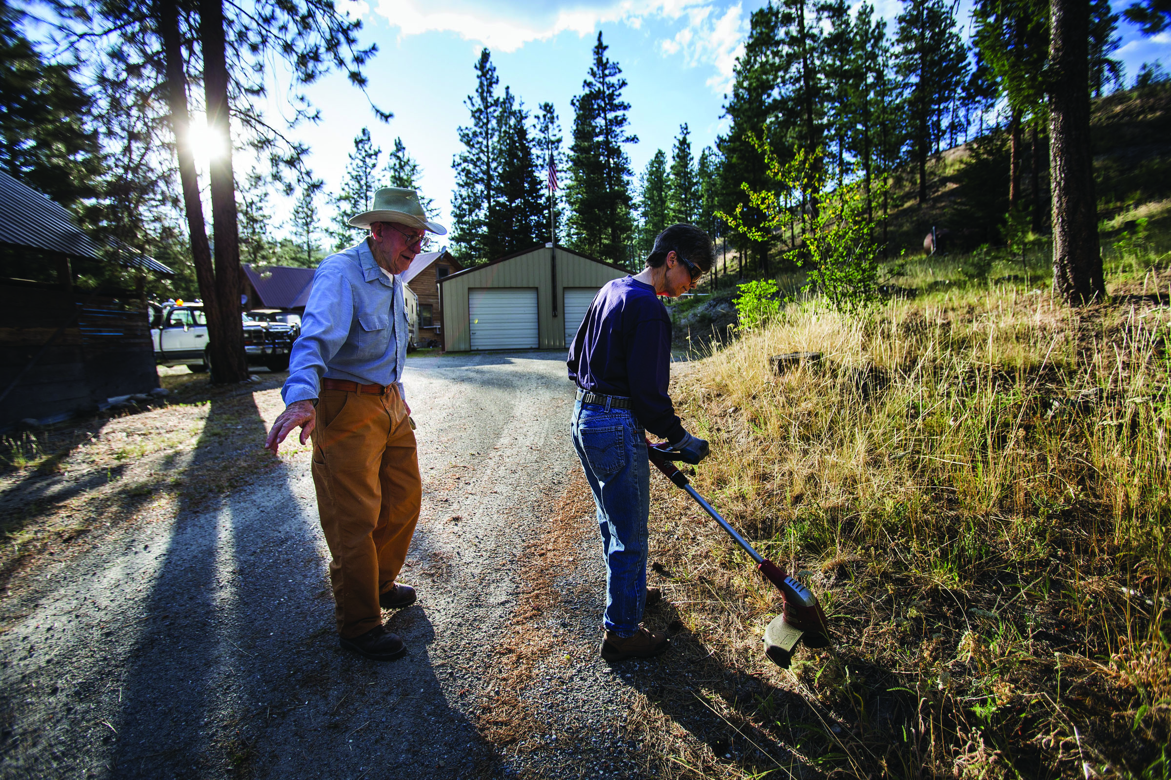 Peggy Kelly cuts back grasses as Noble Kelly supervises at their home in the Chiliwist area of Okanogan County. With the Kellys leading about 40 property owners