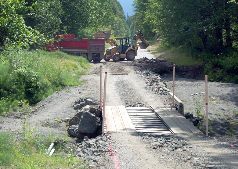 An excavator loads pieces of old roadway into a dump truck last week at the site of a washout on Olympic Hot Springs Road in the Elwha Valley of Olympic National Park. The road was heavily damaged by floods last winter. Two campgrounds in the valley remain closed due to flood damage. — Keith Thorpe/Peninsula Daily News ()
