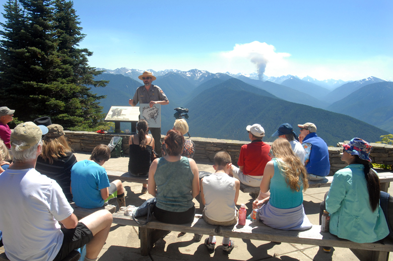 Education Ranger John Stoeckl gives a talk on the outdoor patio at the Hurricane Ridge Visitor Center in Olympic National Park as the Hayes Fire sends up a plume of smoke in the distance on Friday. — Keith Thorpe/Peninsula Daily News ()