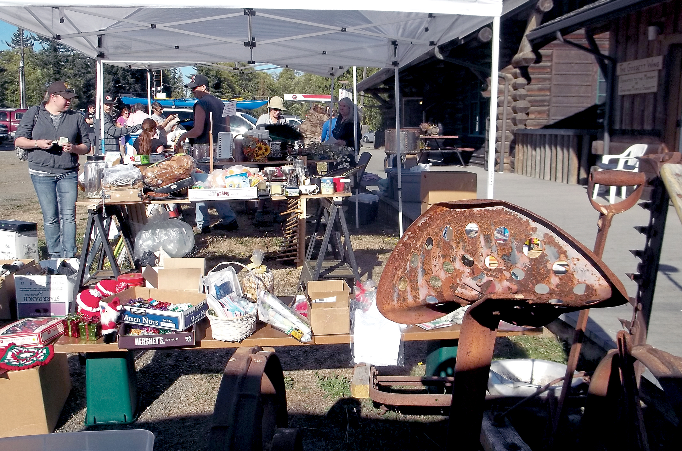 Visitors look over the goods on display at the community sale in Joyce during the 2013 Great Strait Sale. — Juan de Fuca Scenic Byway Association