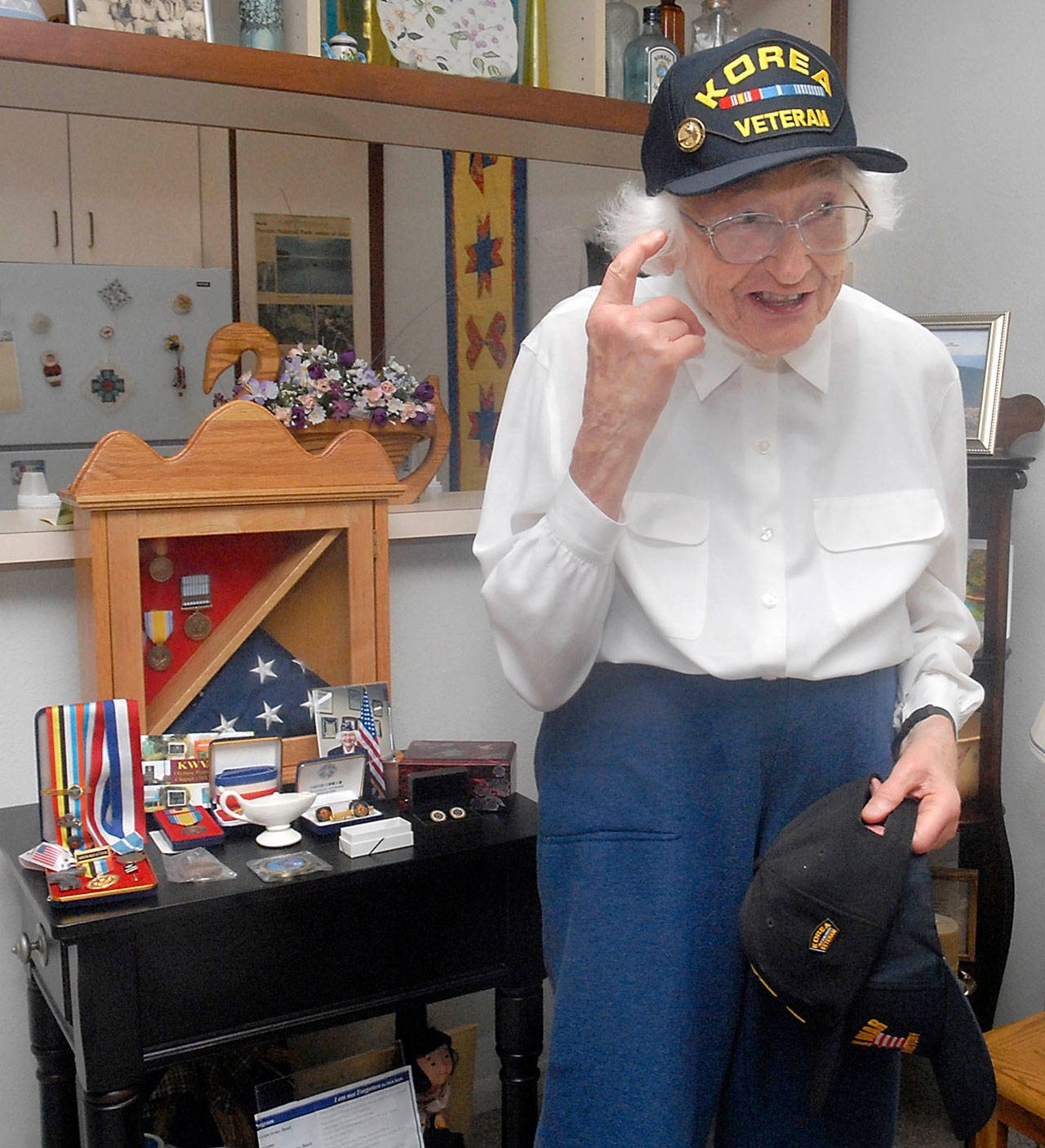 Mary Reid of Port Angeles, 90, a U.S. Army veteran of the Korean War, shows of one of her many caps that distinguish her service to her country. (Keith Thorpe/Peninsula Daily News)