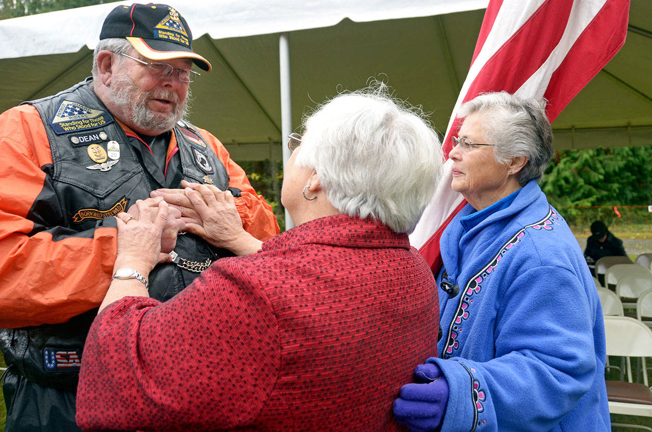 Joan Shields Bennett, widow of Navy Seabee Medal of Honor recipient Marvin G. Shields, and her sister Esther Alward gave a seabee challenge coin to Dean Thiem of the patriot guard riders after a Veterans Day event at the Gardiner cemetery on Saturday. (Cydney McFarland/Peninsula Daily News)