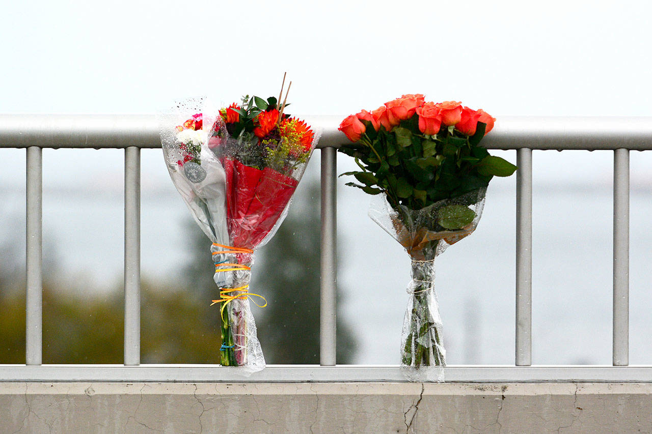 Flowers lean against the rail of the east Eighth Street bridge from which a Port Angeles High School student jumped to her death Monday. (Jesse Major/Peninsula Daily News)