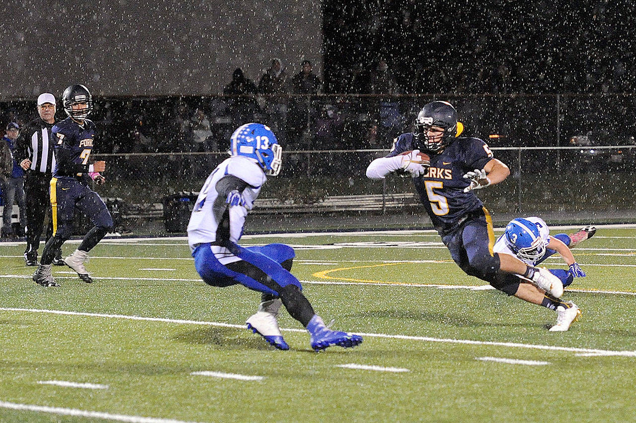 Cole Baysinger (5) avoids Elma defenders Brady Shriver (3) and Cody Vollan (13) as the rains begin to fall Friday night at Spartan Stadium. Looking on is Forks QB Gabriel Reaume (7). (Lonnie Archibald/for Peninsula Daily News)