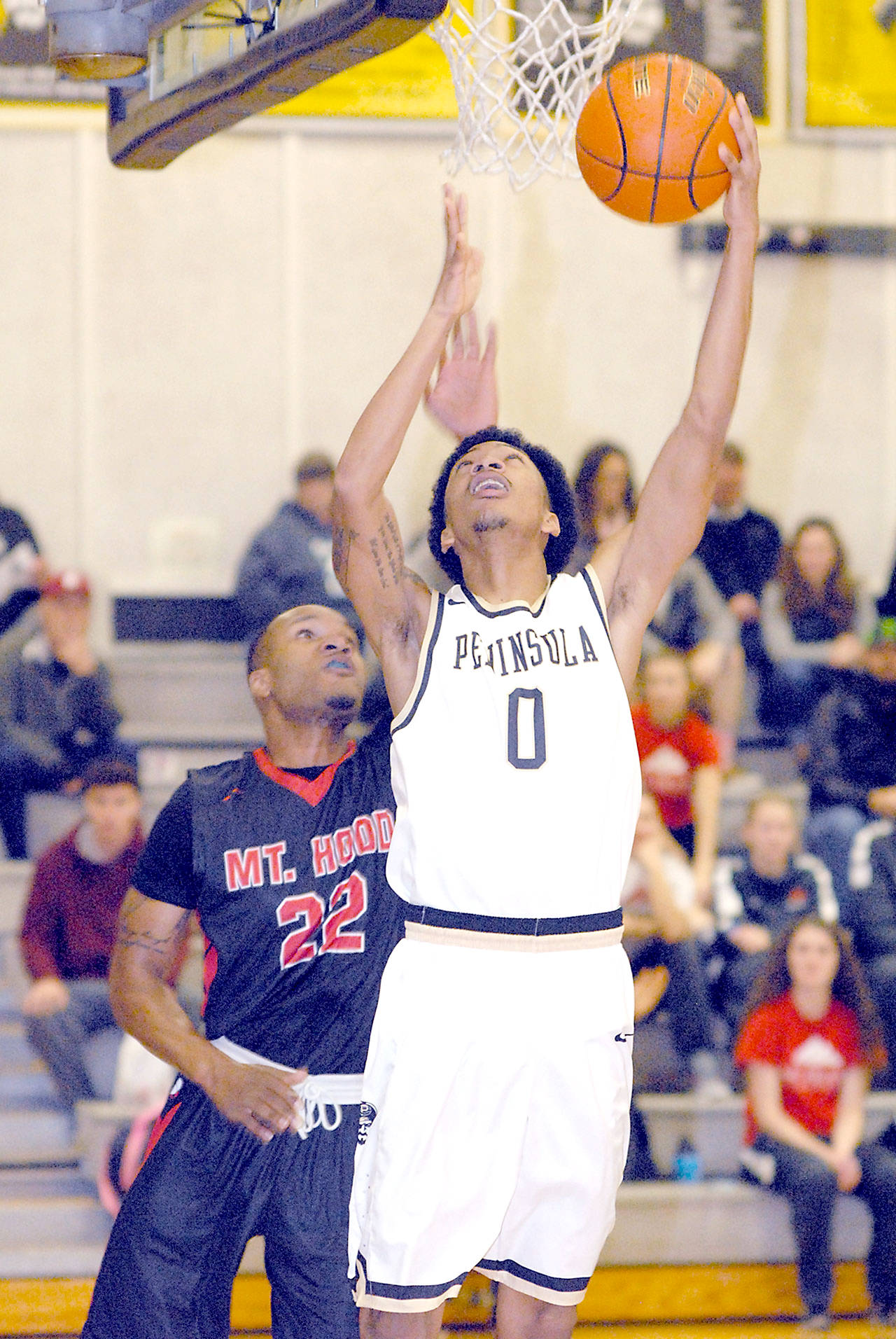 Keith Thorpe/Peninsula Daily News Peninsula’s Elijah Williams, front, goes for the layup in front of Mount Hood’s Steven Fair in the first half of the Pirate’s season opener on Saturday in Port Angeles.
