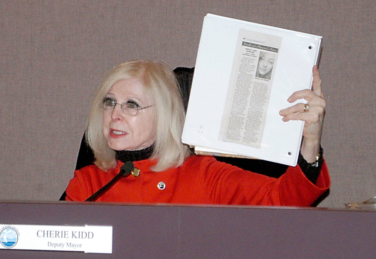 Port Angeles Deputy Mayor Cherie Kidd holds up a notebook containing an obituary for Ashley Wishart, who died after jumping from the eastern Eighth Street bridge Nov. 13. Kidd is working with state representatives to fund taller barriers for the Eighth Street bridges. (Rob Ollikainen/Peninsula Daily News)