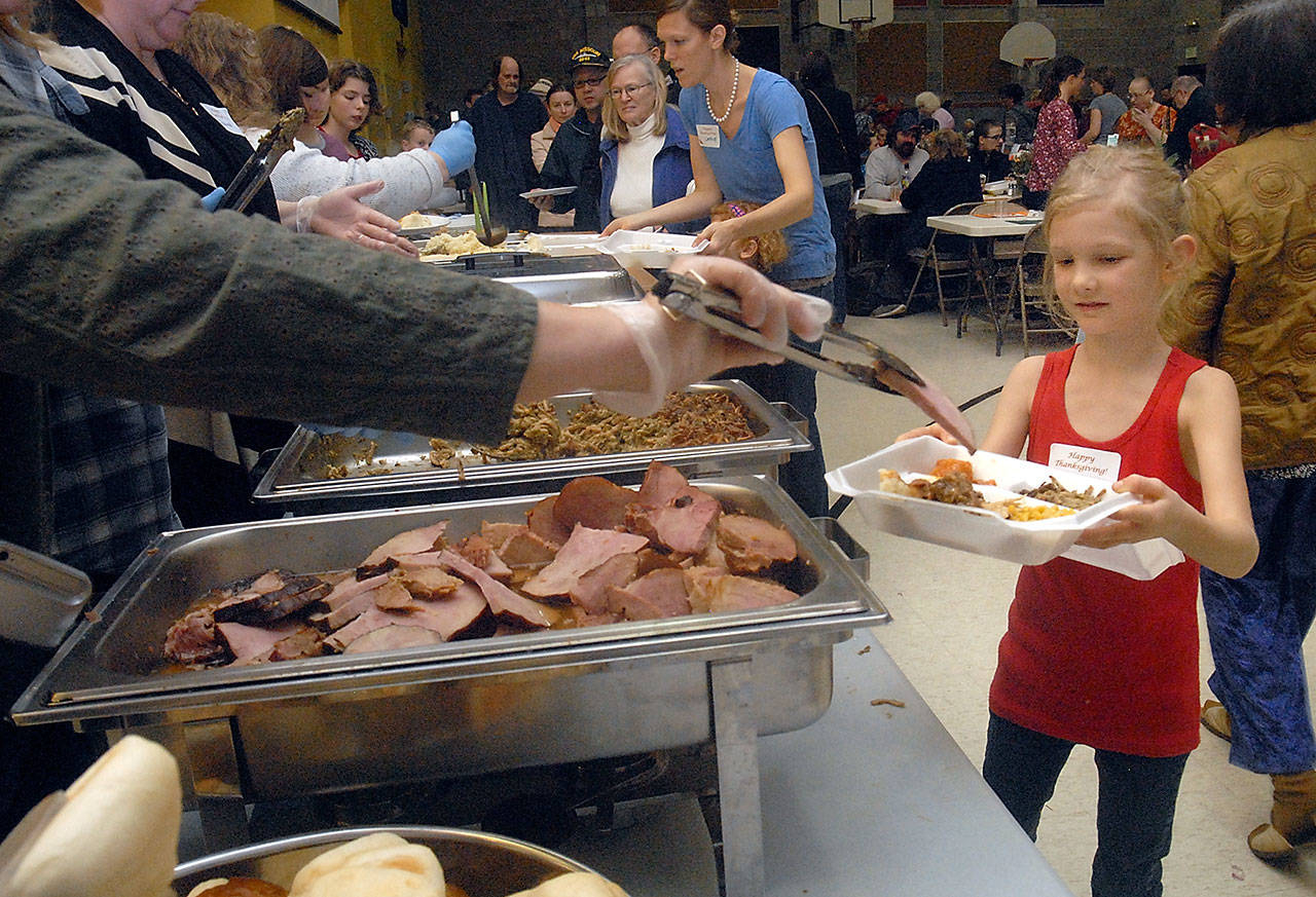 Volunteer Ellie Karjalainen, 7, of Port Angeles, right, helps with a to-go container of food during Thursday’s community Thanksgiving dinner in the gym of Queen of Angels Catholic Church in Port Angeles. (Keith Thorpe/Peninsula Daily News)