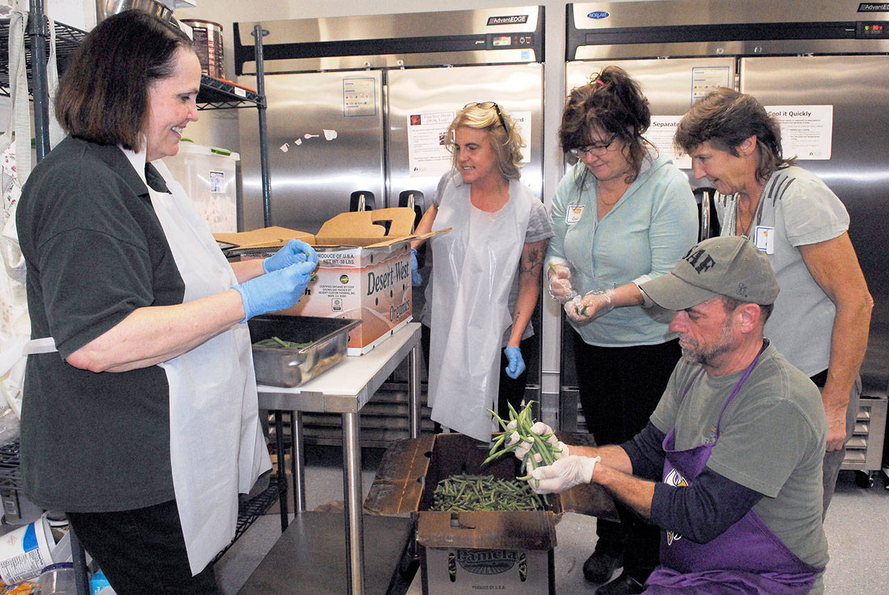 Last-minute green bean prep before the big event involves, from left, coordinator Rita Hubbard, Violet Nelson, Cordi Fitzpatrick, Cher Albright and chef John Foss. (Jeannie McMacken/for Peninsula Daily News)