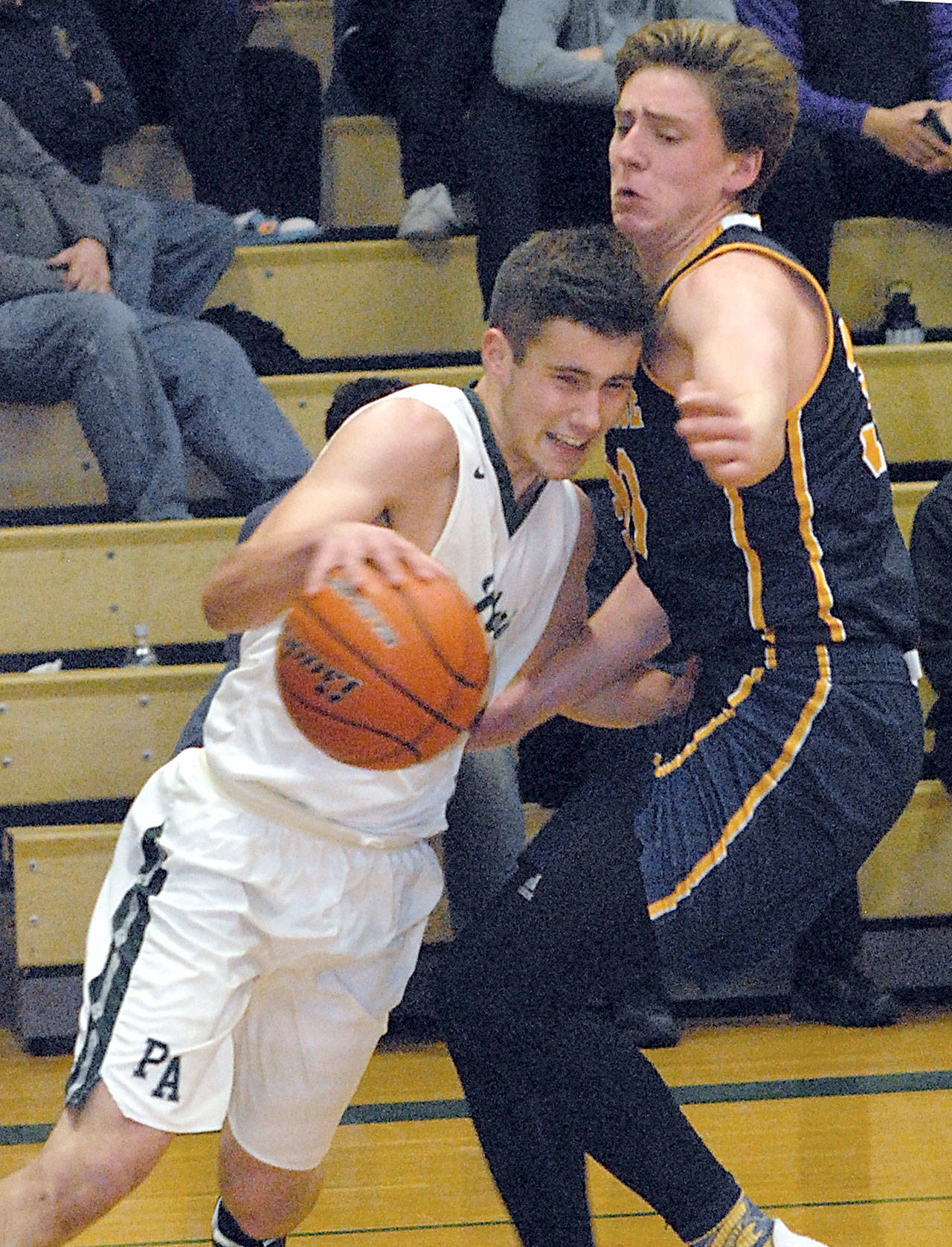 Port Angeles’ Kyle Benedict, left, drives to the lane past Bainbridge’s Charlie Hoberg in the first quarter of Tuesday night’s game at Port Angeles High School. (Keith Thorpe/Peninsula Daily News)