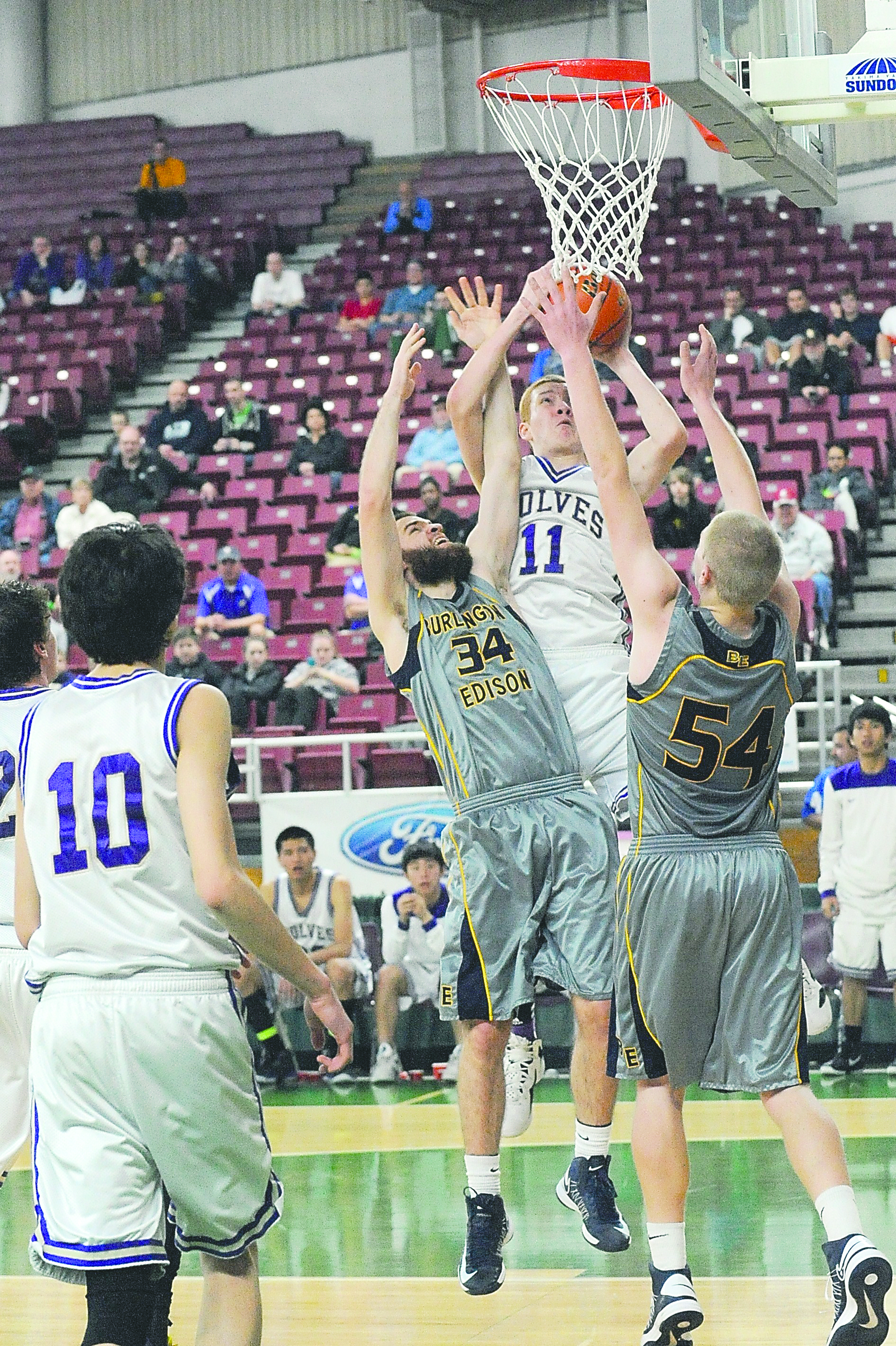 Sequim's Rory Kallappa attempts a shot against Burlington-Edison's Daron Browning (34) and Austin Van Herbulis (54) in the 2A fourth-place semifinals at the Yakima Valley SunDome on Friday. Lonnie Archibald/for Peninsula Daily News