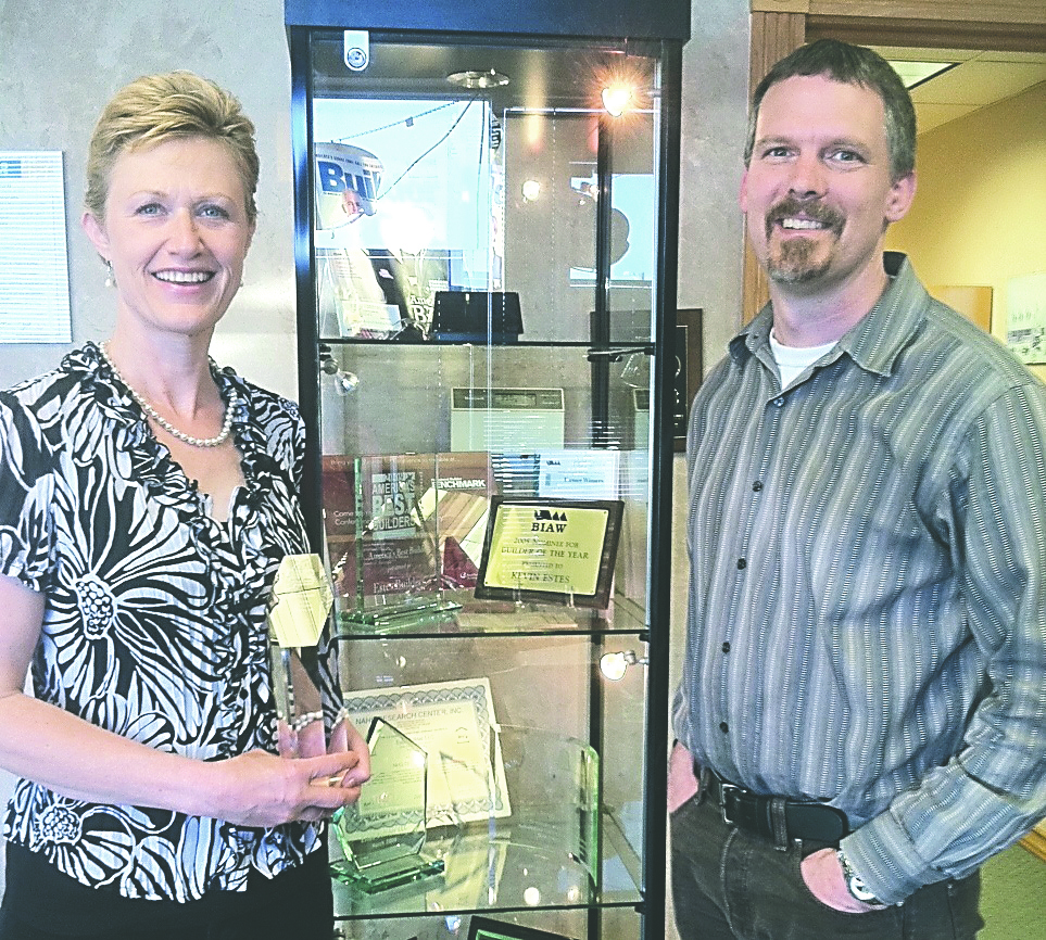 Nell Clausen and Rick Gross of Estes Builders display the Avid Diamond Award and other honors won by the custom-home builder.
