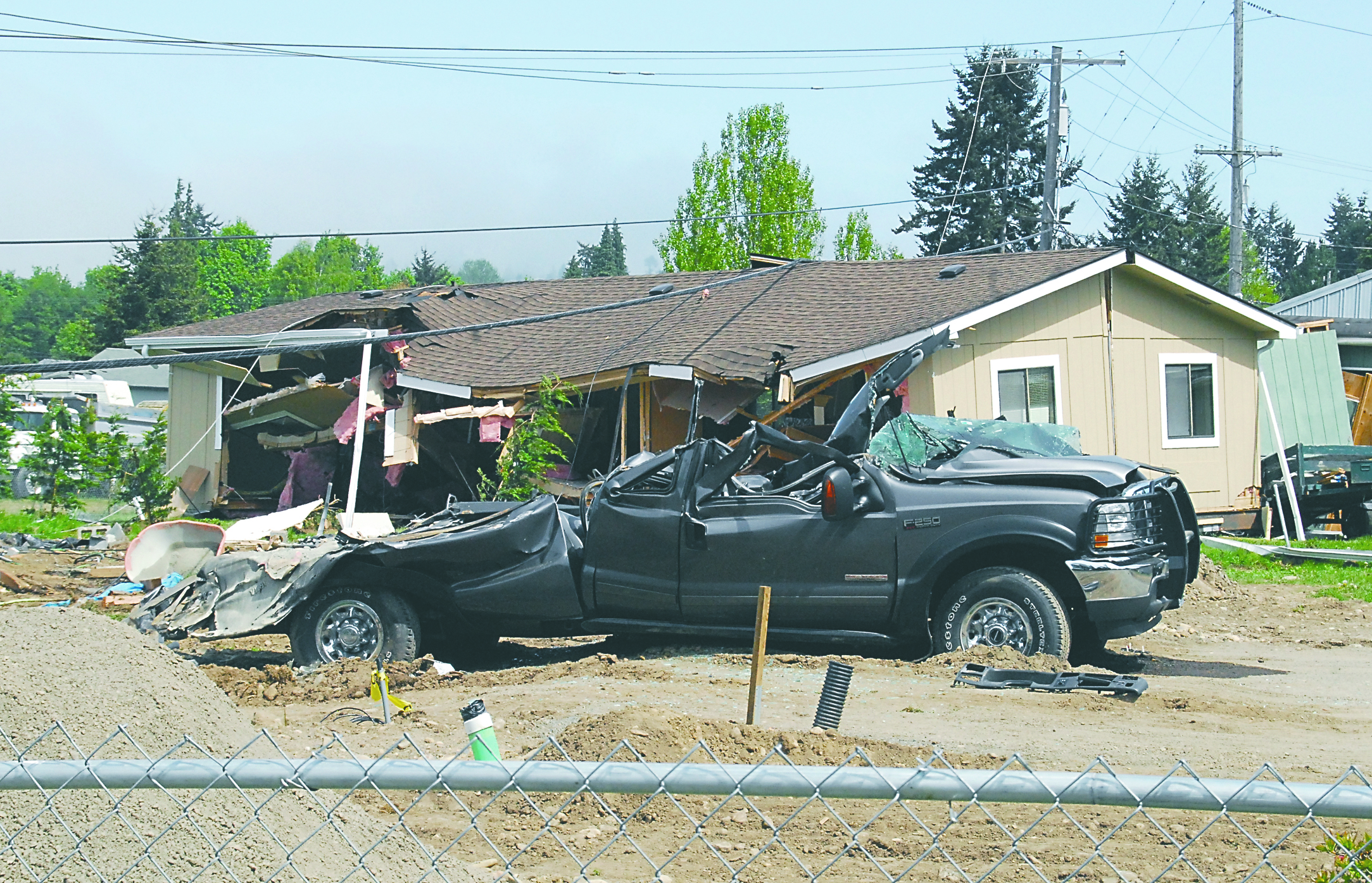 A crushed truck and a house knocked off its foundation sit as part of the aftermath of a rampage by a man driving a logging bulldozer on Friday in the Gales Addition east of Port Angeles.  Click on "Related Photos" icon below to see more photos. Keith Thorpe/Peninsula Daily News (Click to enlarge)