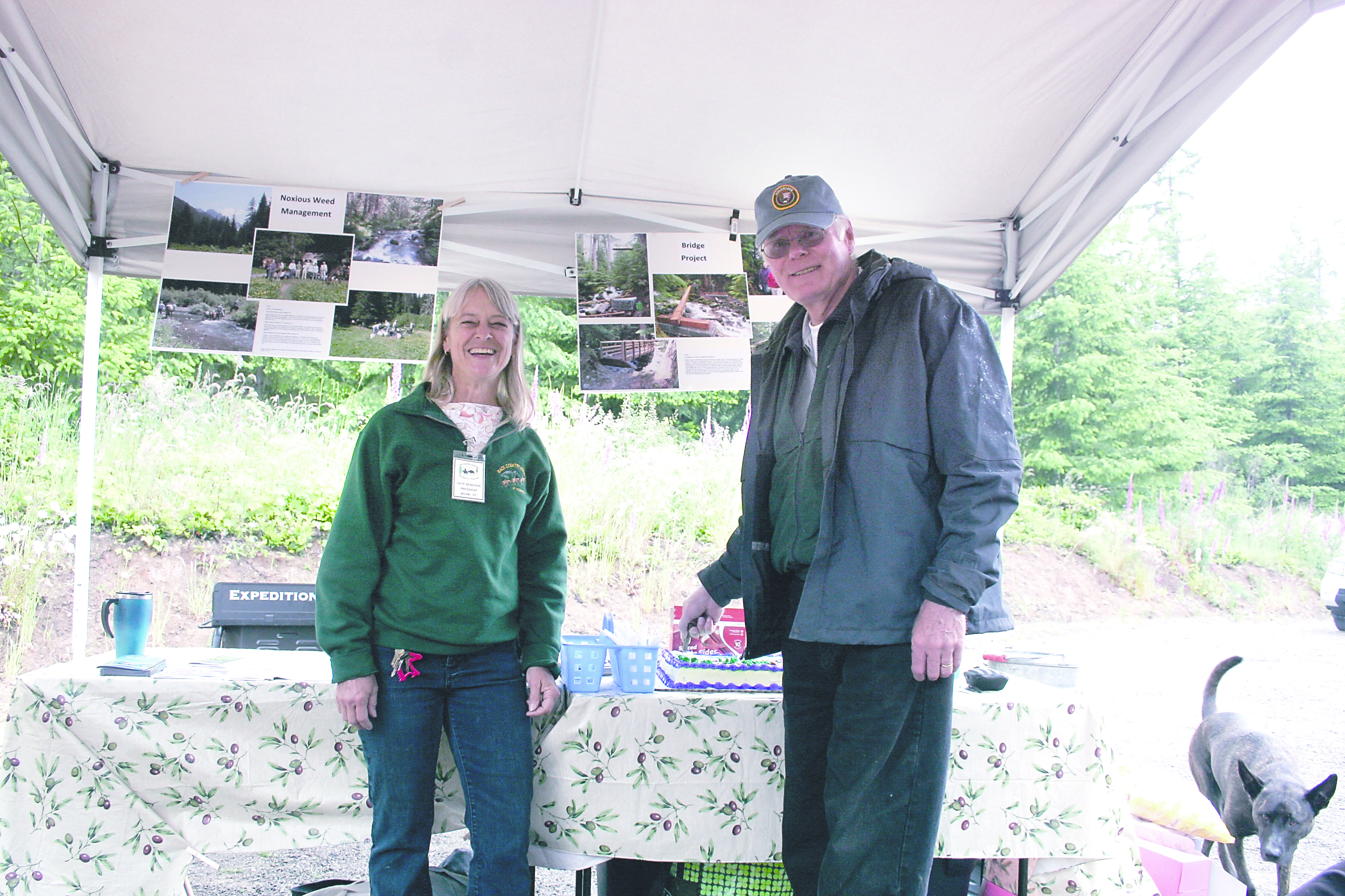 Backcountry Horsemen Peninsula Chapter's Cate Bendock and Project Manager Tom Mix cut the ceremonial cake during dedication ceremonies for the Dan Kelly Olympic Discovery Trail trailhead parking area on June 22. Karen Griffiths/For Peninsula Daily News