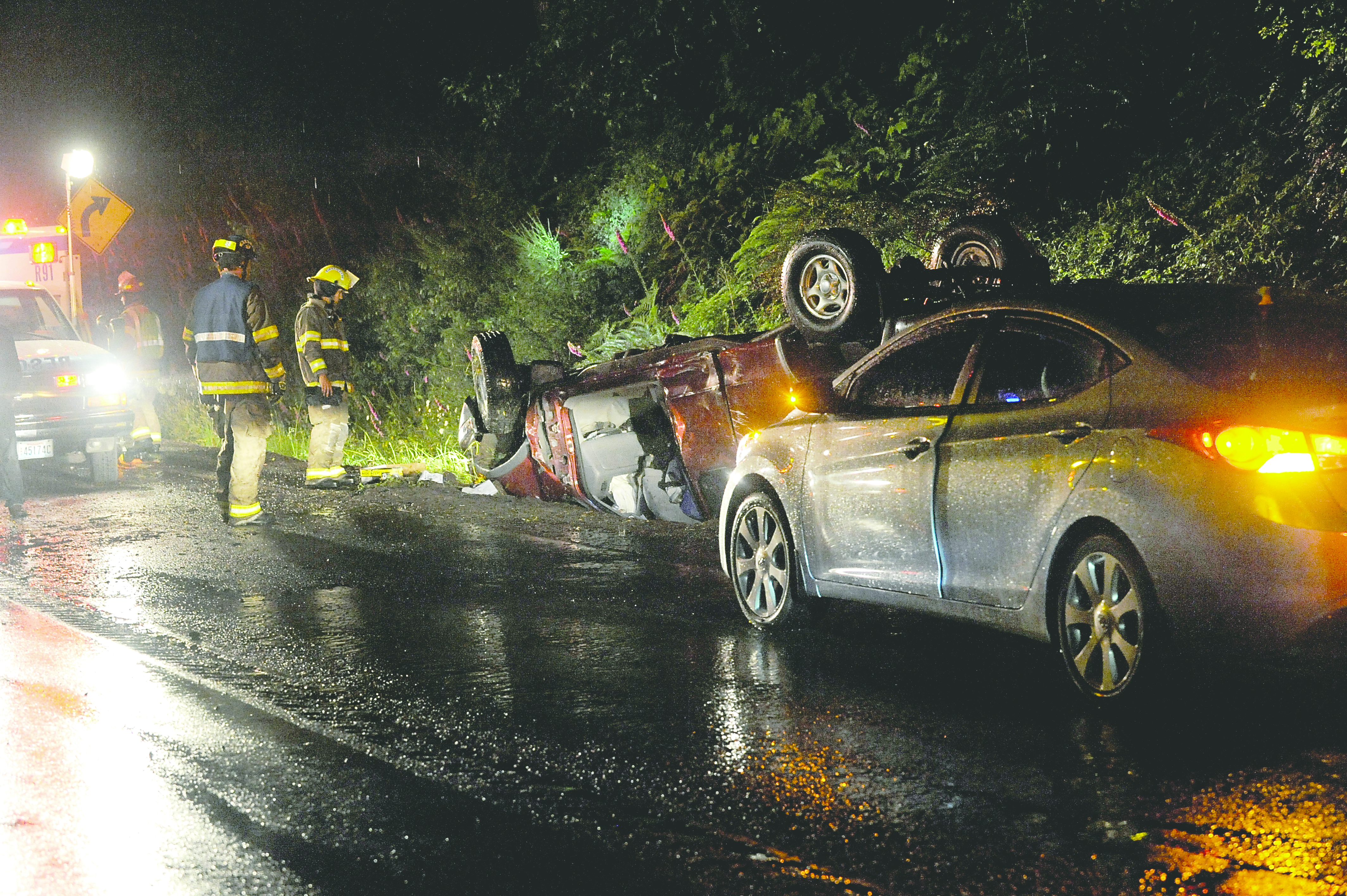 Forks firemen from Clallam County Fire District No. 1 inspect an overturned vehicle on U.S. Highway 101 a mile south of Forks early Saturday morning. Lonnie Archibald/for Peninsula Daily News