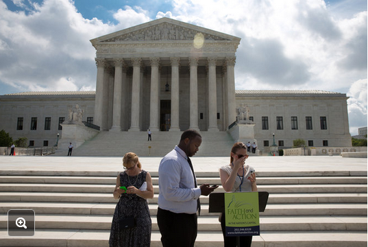 Activists — with their cellphones — in front of the Supreme Court on Wednesday. The Associated Press