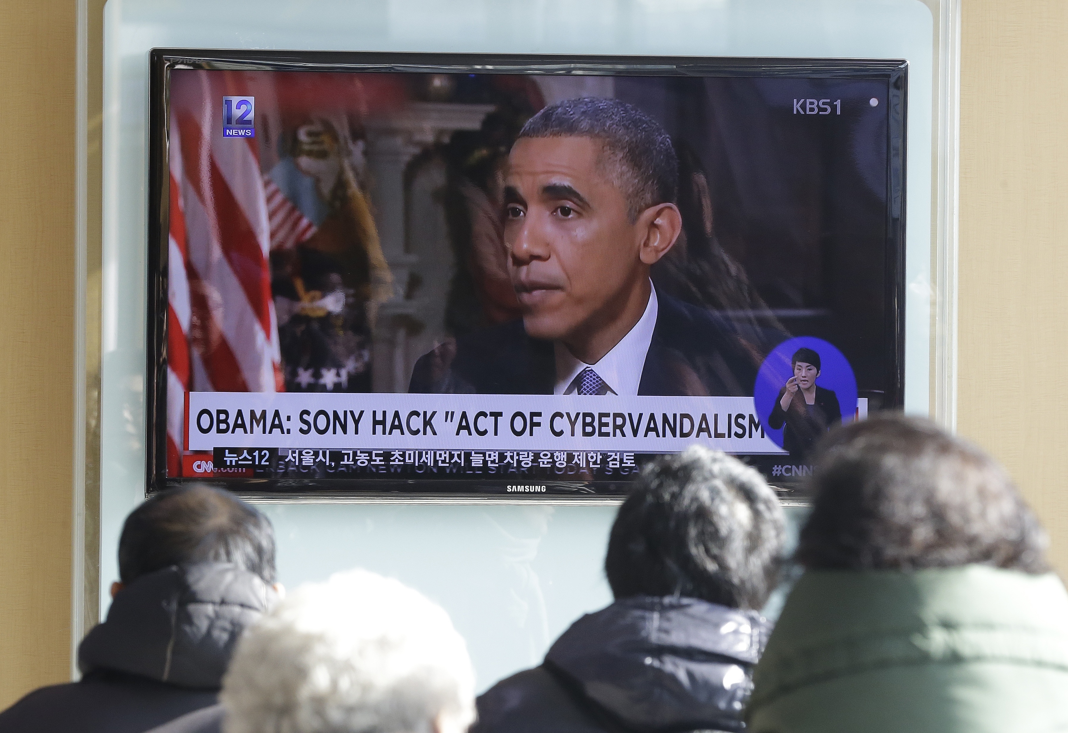 People watch a TV news program showing U.S. President Barack Obama at the Seoul Railway Station in Seoul