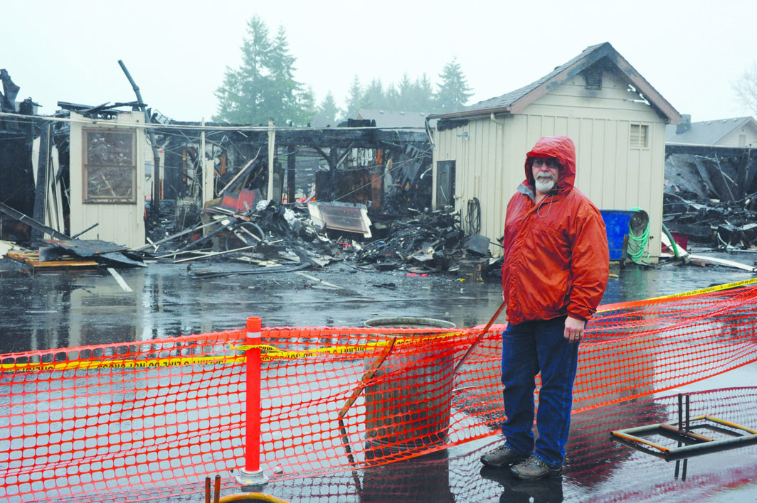 Dave Cole of the stat Department of Natural Resources stands in front of the burned-out building in Forks on Monday. Lonnie Archibald/Peninsula Daily News